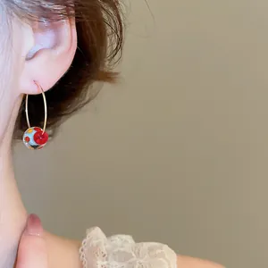 Primo piano di un orecchino a cerchio con sfera in resina colorata e punti vivaci sul modello