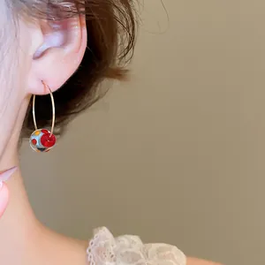 Primo piano di un orecchino a cerchio con sfera in resina colorata su modella, chic.