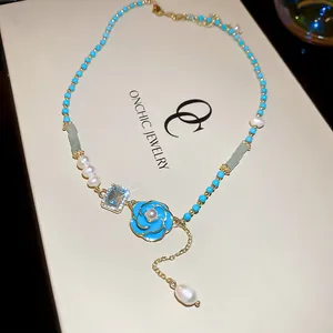 Detailed close-up of blue floral enamel pendant and freshwater pearl necklace on jewelry gift box