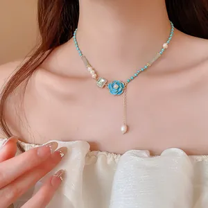 Close-up view of elegant blue enamel flower necklace with freshwater pearls on a model