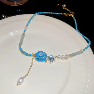 Detailed view of a sweet blue flower enamel necklace with freshwater pearls on a white plate.
