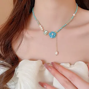 Elegant close-up shot of a sweet blue flower pendant necklace with freshwater pearls and beads