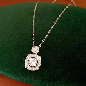 Elegant silver-toned square geometric pendant necklace with sparkling zircons on green velvet