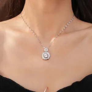 Close-up of an elegant silver necklace with a square zircon pendant worn on a female model