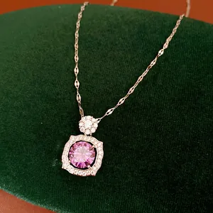 Detail shot of a zircon pendant necklace with a pink stone on a green velvet stand.