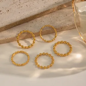 Detail shot of five stacked 18K gold plated minimalist rings on a marble surface