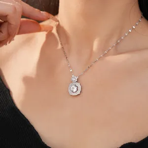 Close-up detail of geometric silver pendant necklace featuring a shimmering zircon center