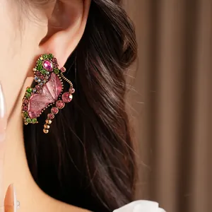 Close-up of vintage butterfly earring with pink resin wing and colorful rhinestones