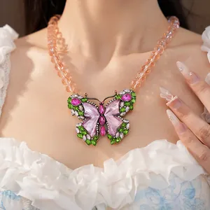 Close-up of vintage butterfly pendant with colorful resin stones and beaded chain
