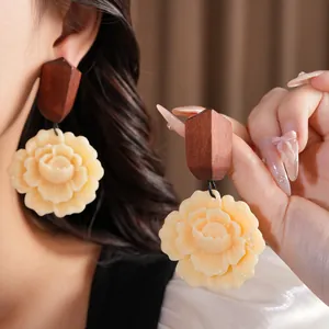 Detailed close-up of vintage wood and resin flower drop earrings worn by a model