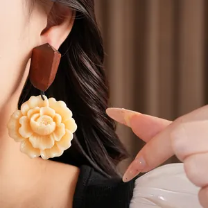 Close-up detail of retro ethnic style wood and resin flower earrings with silver needles