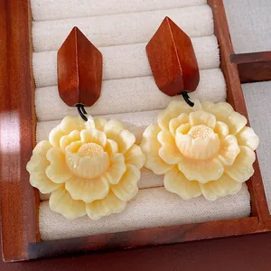 Detail view of vintage cream resin flower earrings with geometric wooden top in a tray