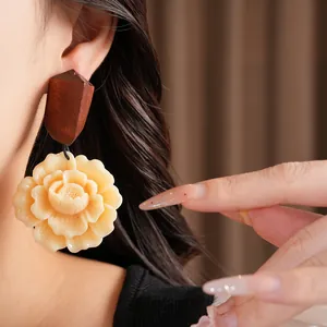 Macro detail shot of large cream resin flower earrings with dark wood stud on model