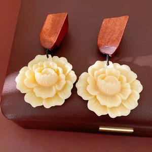 Detailed close-up of handmade wood and resin flower earrings on a brown leather jewelry box.