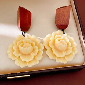 Detailed macro view of retro wood and resin flower drop earrings in a jewelry box