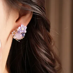 Eleganti orecchini a fiore in resina con zirconi viola e perla rosa sull'orecchio
