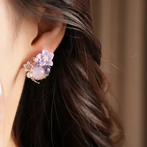 Primo piano di orecchini a fiore in resina viola con perla rosa su orecchio