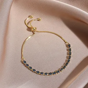 Detail of adjustable gold bracelet with sparkling blue teardrop zircons on satin fabric