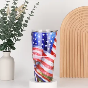 Detail of 30oz tumbler with American flag design and clear lid on a white display stand