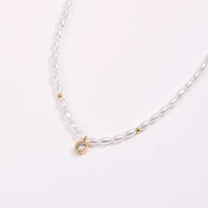 Detail einer Perlenkette mit Goldperlen und Diamantanhänger auf weißem Grund