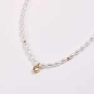 Detail einer eleganten Perlenkette mit Goldperlen und einem funkelnden Zirkonia-Anhänger