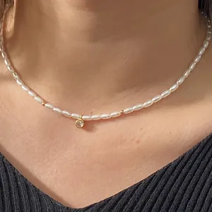 Details einer Perlenkette mit goldenen Akzenten und einem glänzenden Zirkon-Anhänger