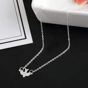 Detailed close-up of a silver dove pendant necklace on a minimalist black and white background