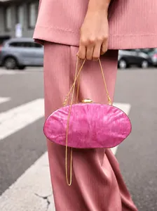 Fashion blogger style fuchsia acrylic marble handbag with golden chain on street