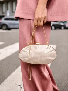 Detail showing marble texture evening bag with gold clasp and chain strap in street style
