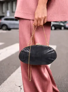 Detail of black marble acrylic shell evening bag with golden hardware and snake chain