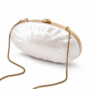 Detail of shell-shaped evening clutch with pearlescent finish and gold chain strap