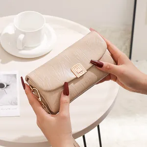 Detail of beige pleated PU leather crossbody bag with golden hardware shown in hand