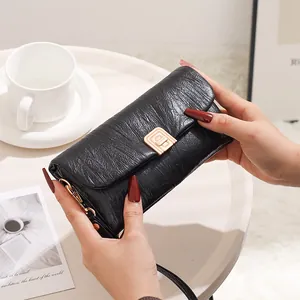 Close-up of black pleated faux leather bag with elegant gold square rotating buckle