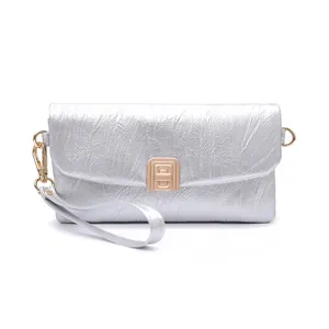 Detail of silver pleated leather clutch featuring a gold rectangular clasp and wrist strap