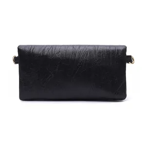 Detail shot of black wrinkled faux leather texture with gold metal rings on a crossbody bag