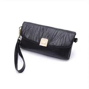 Detailed view of black pleated PU leather clutch bag with golden metal buckle and wristlet