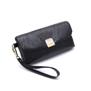 Minimalist black pleated crossbody bag with a gold metal leaf charm and wristlet strap
