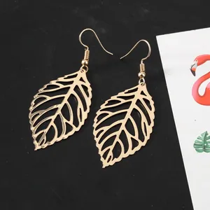 Macro view of gold hollow leaf drop earrings with detailed vein texture on black background