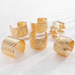 Detailed view of assorted wide gold cuffs with hammered and engraved geometric patterns