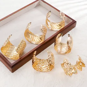 Close-up of assorted gold wide open cuffs featuring hammered and textured geometric patterns