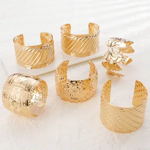 Close-up of textured gold cuff bracelets featuring irregular geometric patterns and engravings