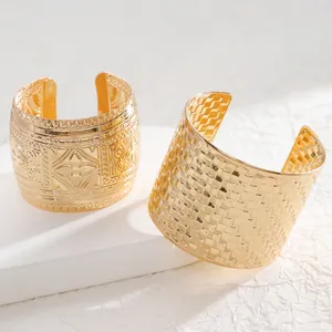 Detail of vintage gold cuff bracelets with embossed floral and woven metal textures
