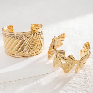 Close-up of golden wide cuff bracelets with spiral texture and bowknot cutout details