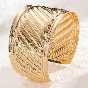 Detailed view of wide gold cuff bracelet featuring irregular leaf vein texture patterns