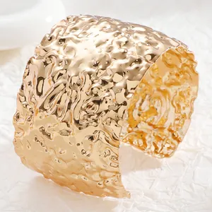 Detailed view of wide gold cuff bracelet featuring irregular hammered metal texture