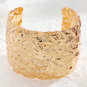 Macro detail of gold wide cuff bracelet with irregular hammered metal texture surface