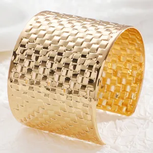 Macro shot of gold wide cuff bracelet showing intricate 3D woven grid texture and shine
