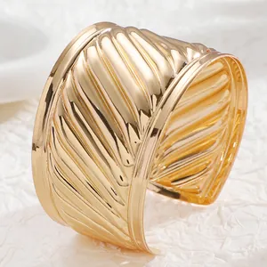 Detailed view of the wavy 3D texture on a wide gold-plated vintage open cuff bracelet
