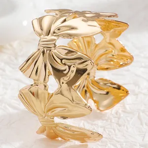 Detailed close-up of a wide gold cuff bracelet featuring linked 3D butterfly motifs