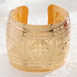 Macro shot of wide gold cuff bracelet featuring intricate geometric embossed textures